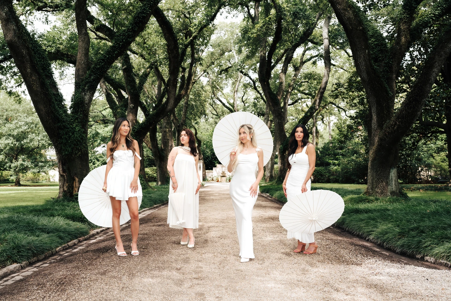 The Beauty Society by Gina team in white dresses on a tree-lined path